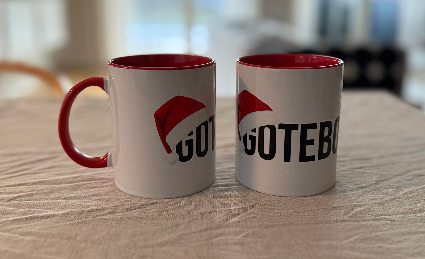 Vit kaffekopp med röda inslag på örat och inuti. Göteborg står skrivet över muggen och en tomteluva täcker början av ordet.