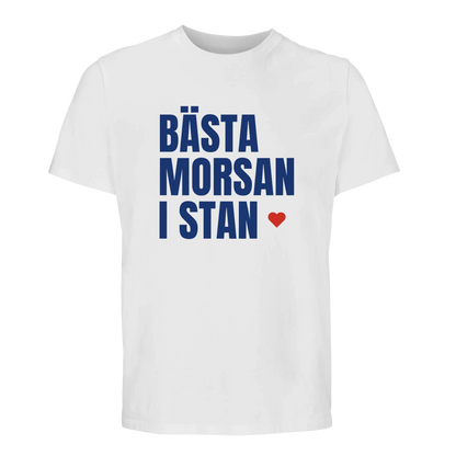 Vit t-shirt med blå text 'BÄSTA MORSAN I STAN' och rött hjärta. Klassisk och somrig modell.