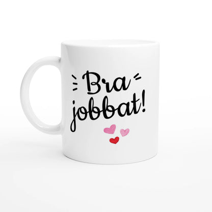 Vit mugg med texten "Bra jobbat!" i svart skrivstil och tre hjärtan