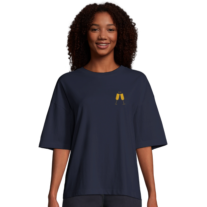 Kvinna bär marinblå oversized t-shirt med champagne-motiv. Modellen visar den boxiga passformen och korta ärmar.