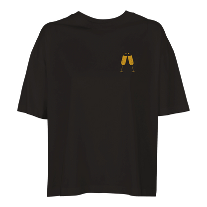 Svart boxy t-shirt för dam med minimalistiskt motiv av två skålande champagneglas i guld.