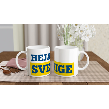 Två helvita kaffemuggar med gult och blått tryck 'HEJA SVERIGE'. En klassisk souvenir från kollektionen för svenska supportrar.