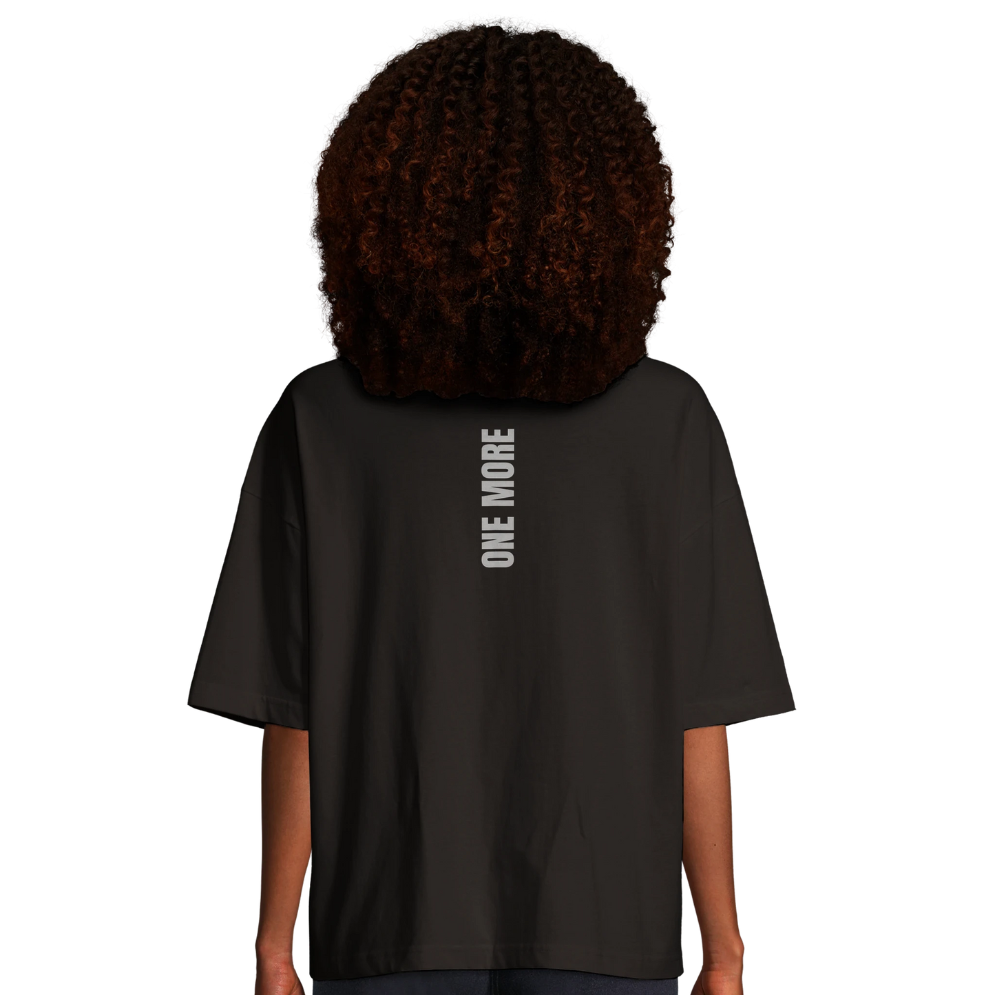 Kvinna sedd bakifrån i en svart oversized boxy tee. Visar det vertikala ryggtrycket och den trendiga passformen.