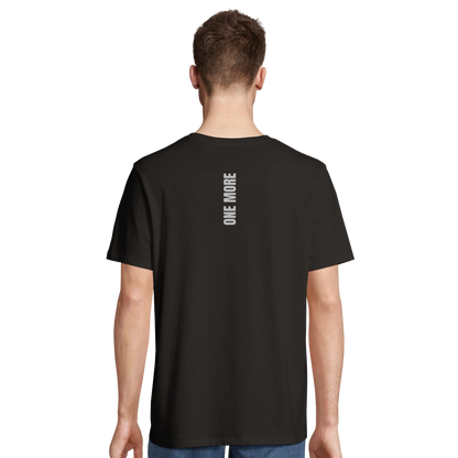 Man i svart One More t-shirt sedd bakifrån, visar den vertikala grafiken på ryggen och tröjans atletiska passform.
