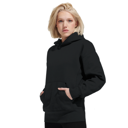 Kvinna i svart oversized huvtröja med rymlig passform och känguruficka. Streetwear-look med fokus på komfort.