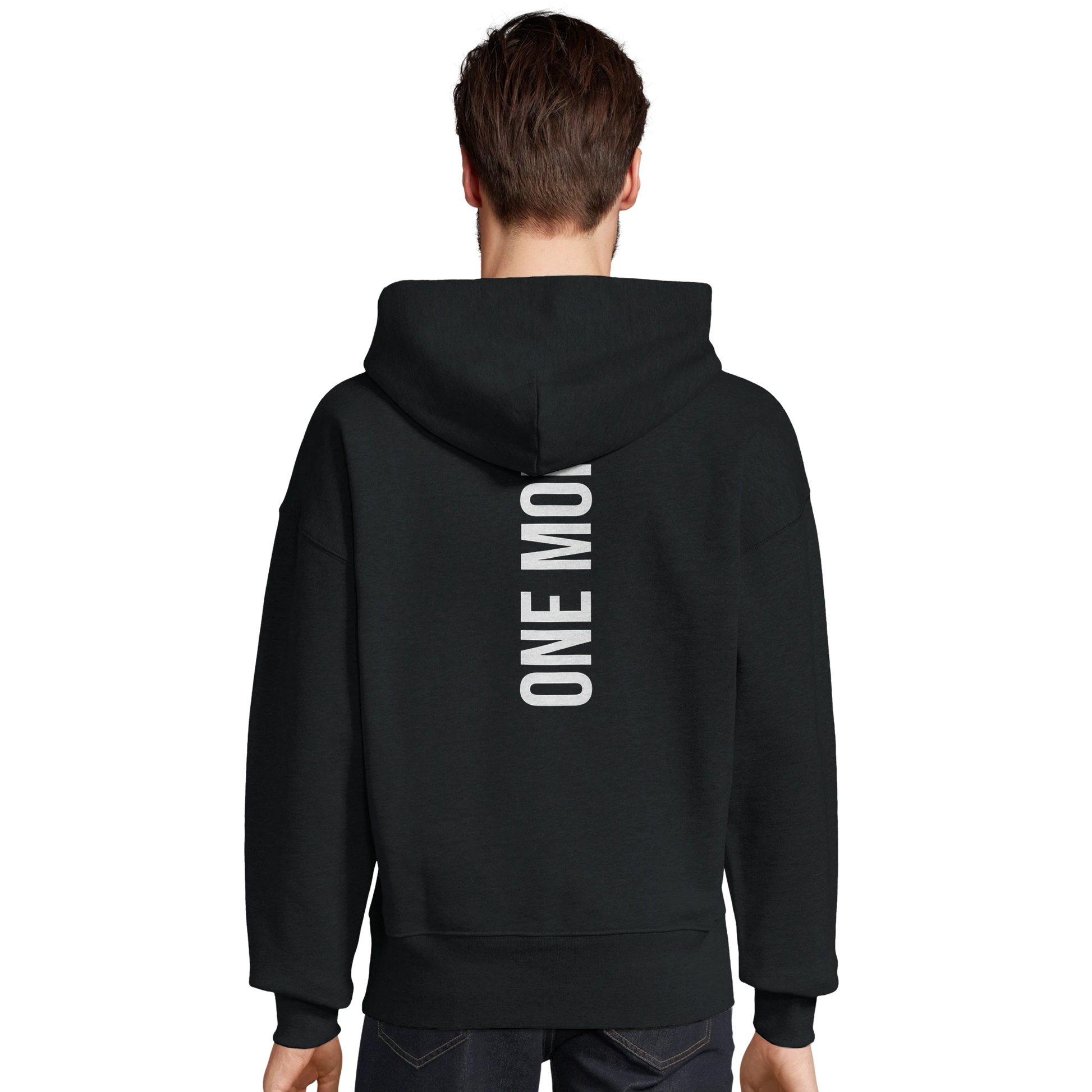 Manlig modell som visar det stora vita ryggtrycket "ONE MORE" på en svart oversized hoodie. Modern passform för träning.