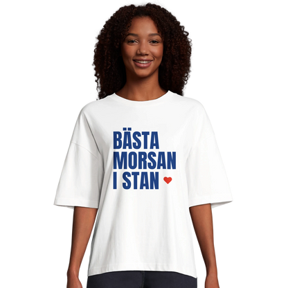 Kvinna i vit oversized t-shirt med texten 'Bästa morsan i stan'. Visar passform och stil för denna populära ekologiska t-shirt.