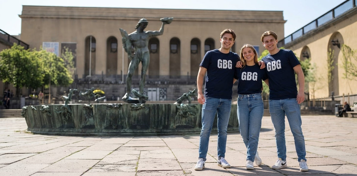 3 unga personer som står framför Poseidon i marinblå t-shirts med texten GBG över bröstet.