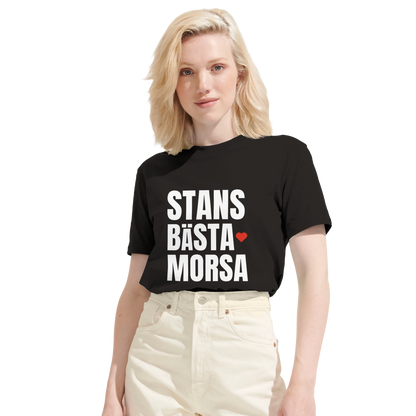 Kvinna bär en svart 'Stans bästa morsa' t-shirt. Bilden visar tröjans passform och det tydliga trycket på bröstet.