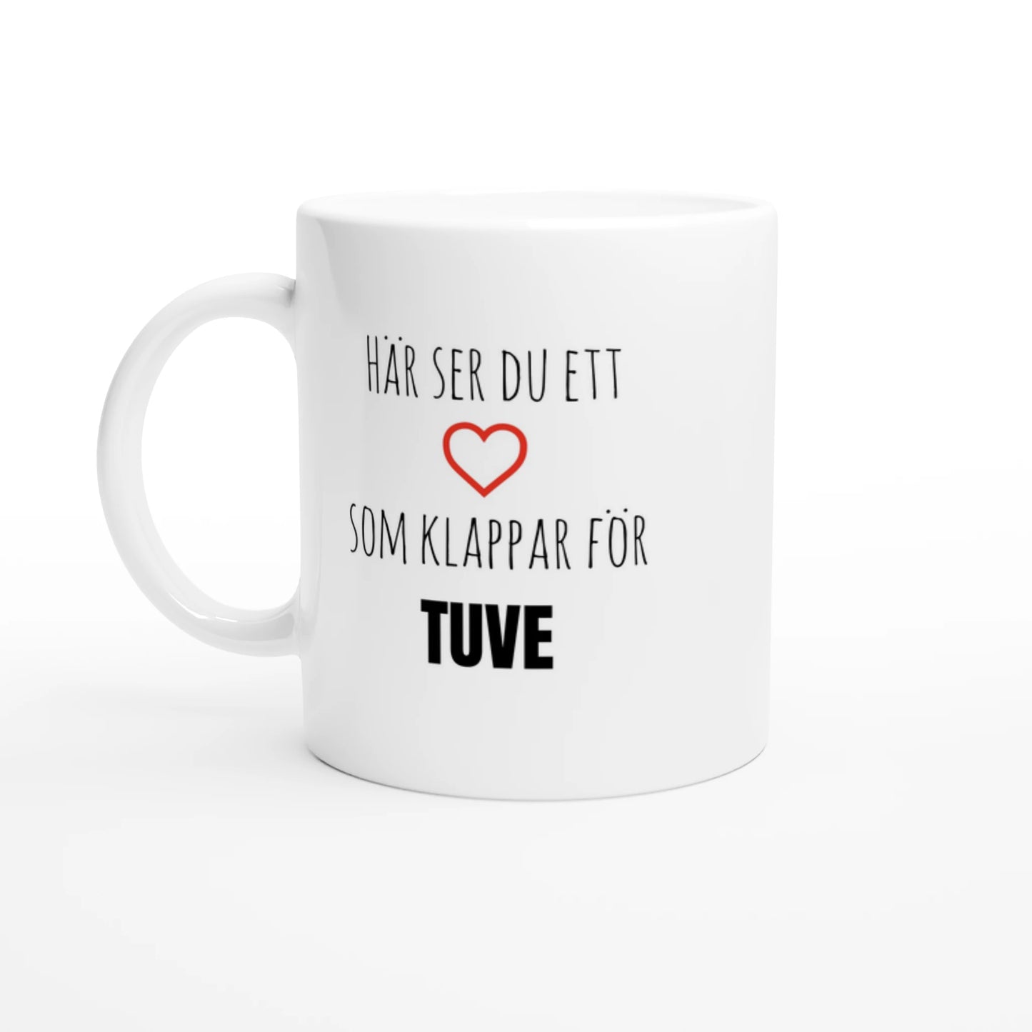 Vit kaffemugg med texten 'Här ser du ett hjärta som klappar för Tuve' och ett rött hjärta. En stilren mugg för alla som älskar Tuve på Hisingen.